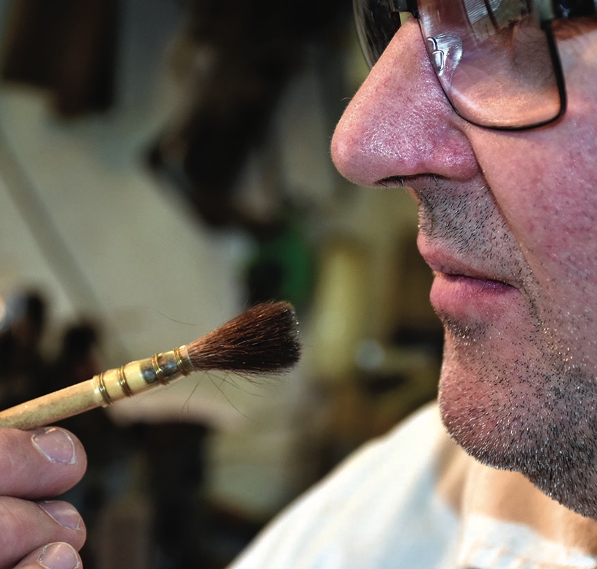 Person closely examining a paintbrush bristles.