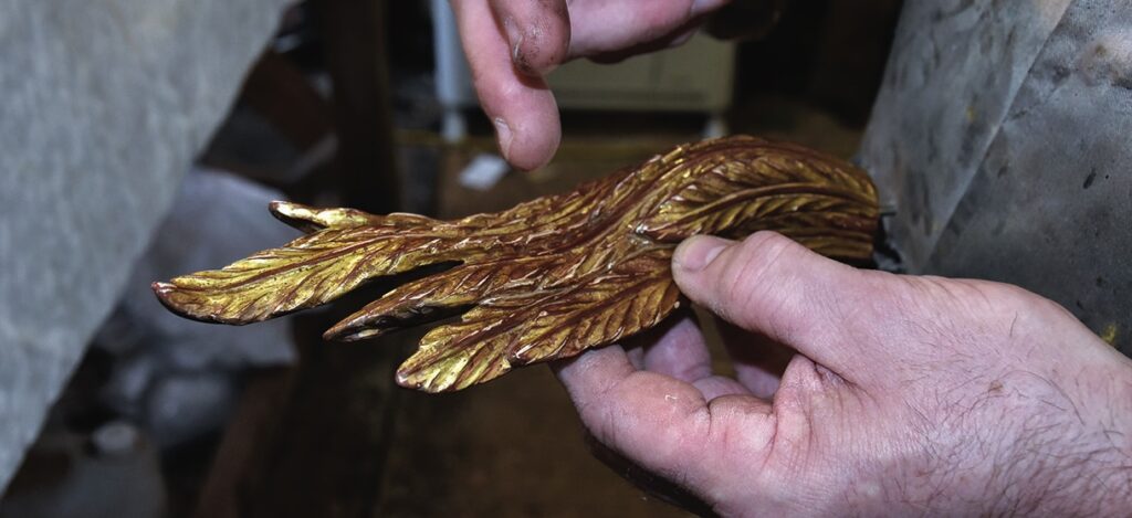 Hands crafting a metallic feather ornament