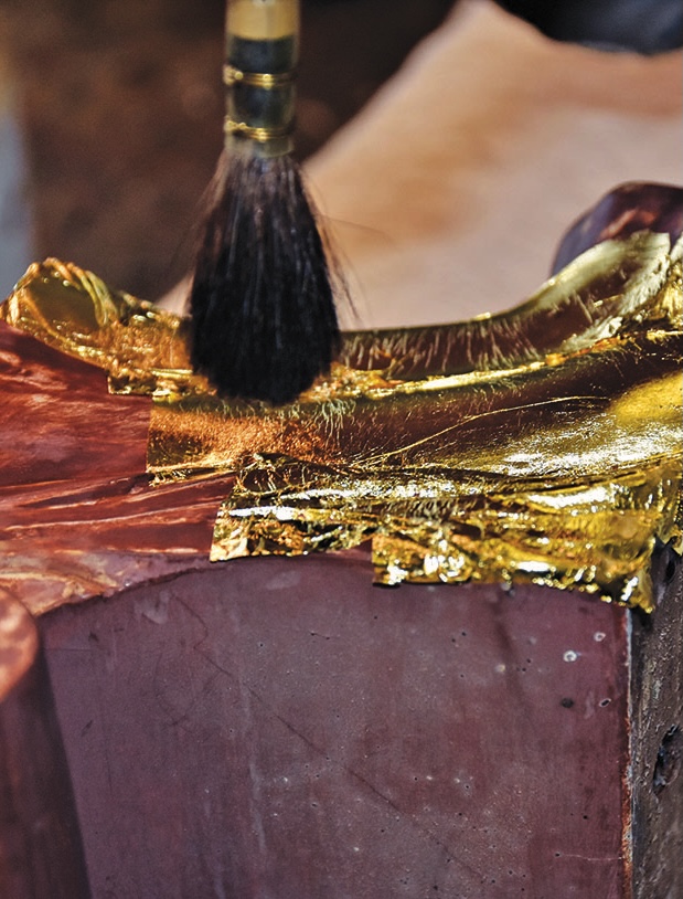 Applying gold leaf with a brush on stone