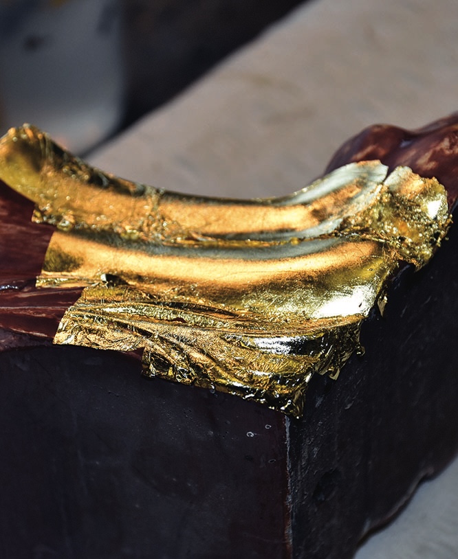 Chocolate cake adorned with gold leaf decoration.