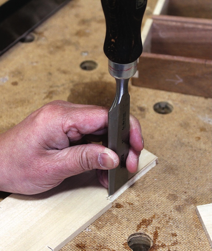 Hand chiselling wood on a workbench.