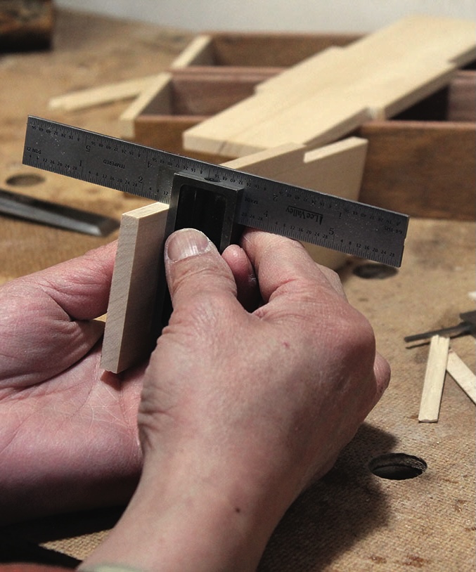 Craftsman measuring wood with a square tool.