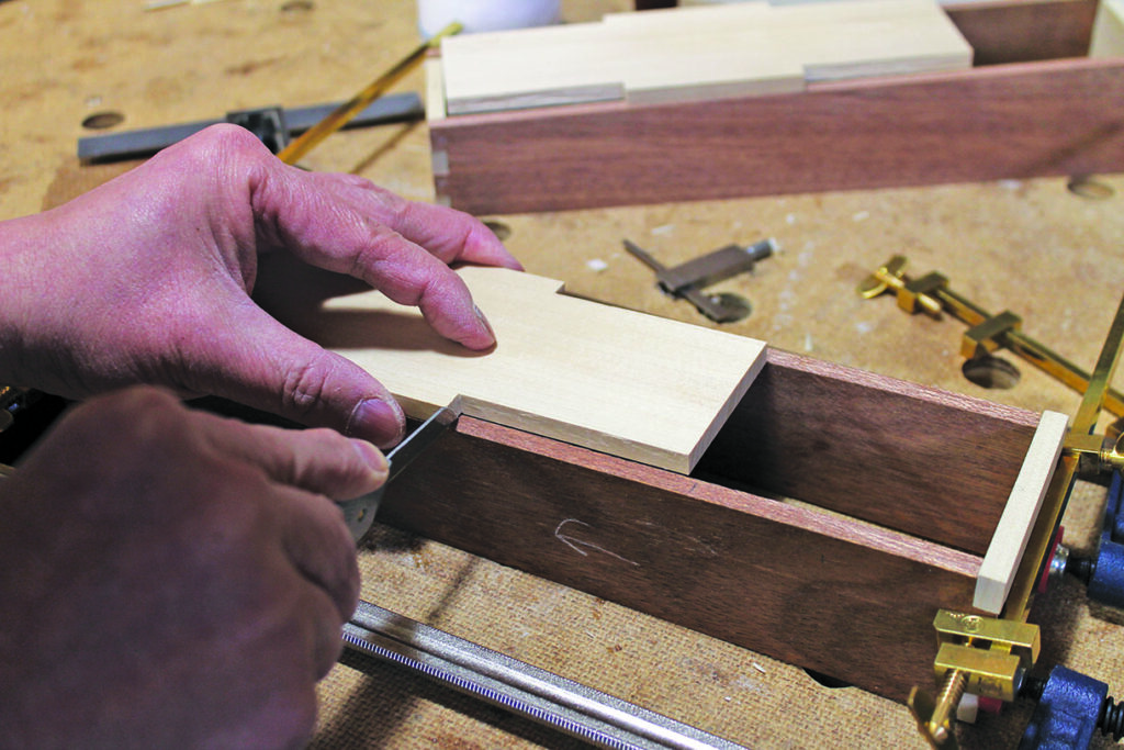 Person crafting wooden joint with precision tool.