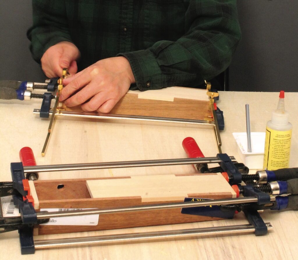 Person clamping wooden pieces with glue on table