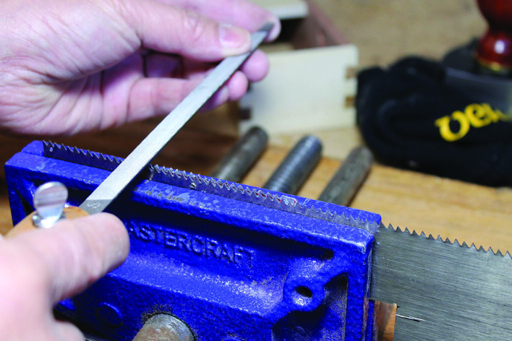 Sharpening a saw blade with a file in vise.