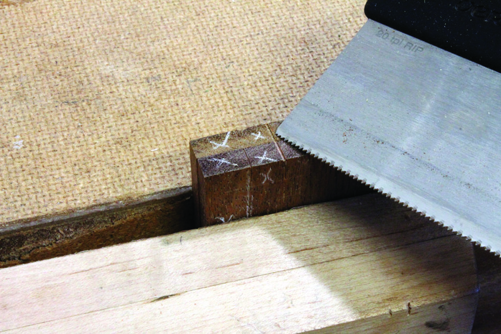 Cutting wood with a hand saw on workbench.