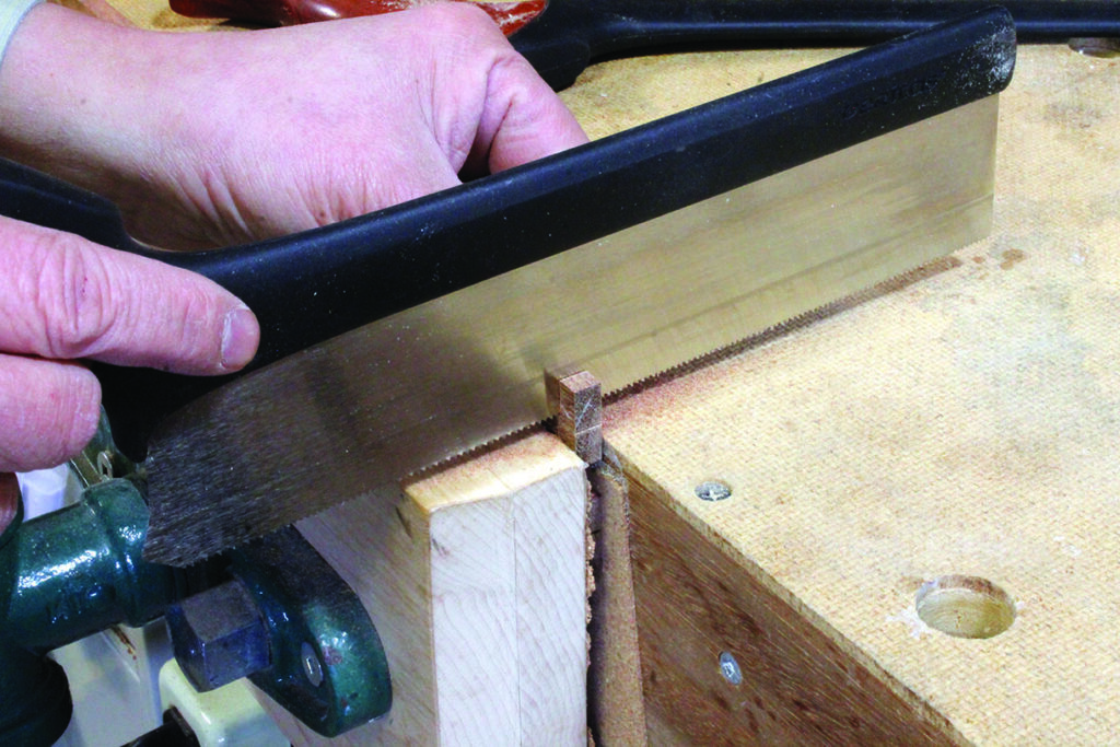 Person sawing wood with a backsaw.