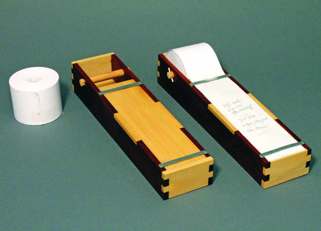 Wooden toilet paper holder with roll and spindle.