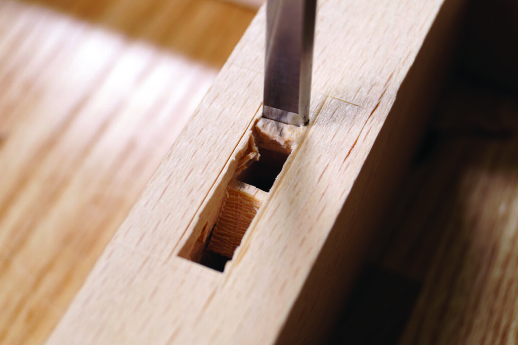 Chisel creating mortise in wooden plank