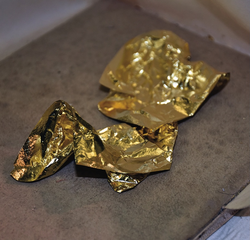 Crumpled gold foil sheets on a surface.