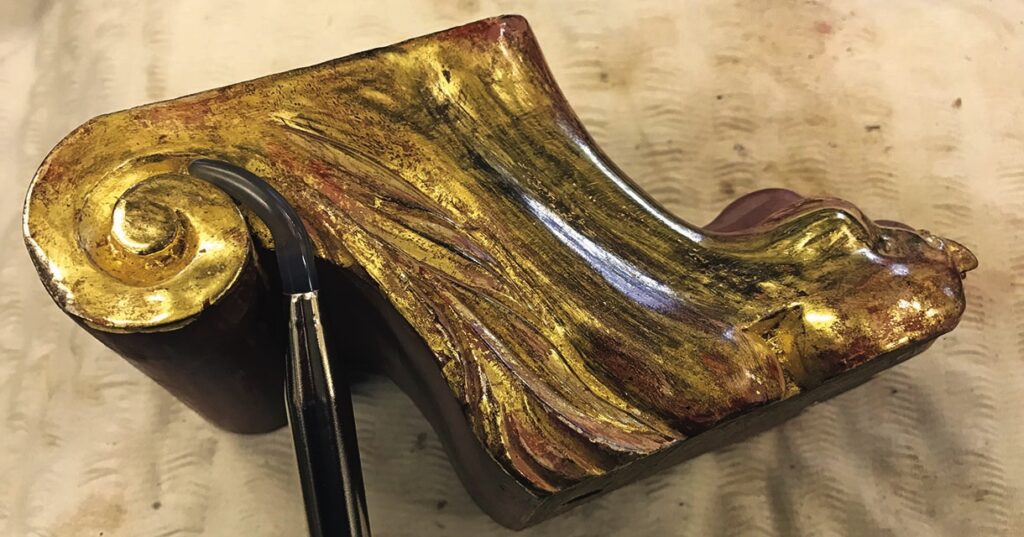 Restored gilded wood carving detail with tool