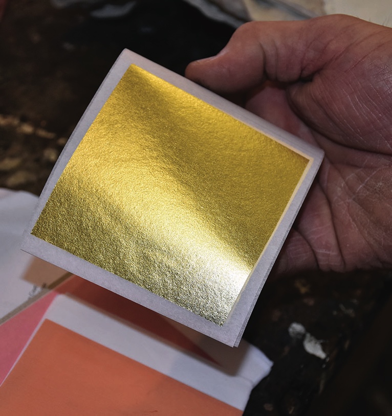 Hand holding a sheet of gold leaf