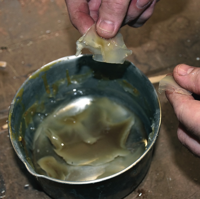 Hands examining substance in a metal container.