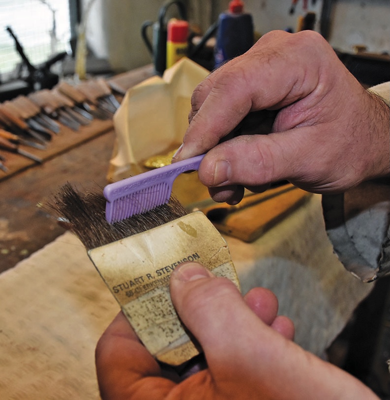 Hands cleaning a brush with a comb