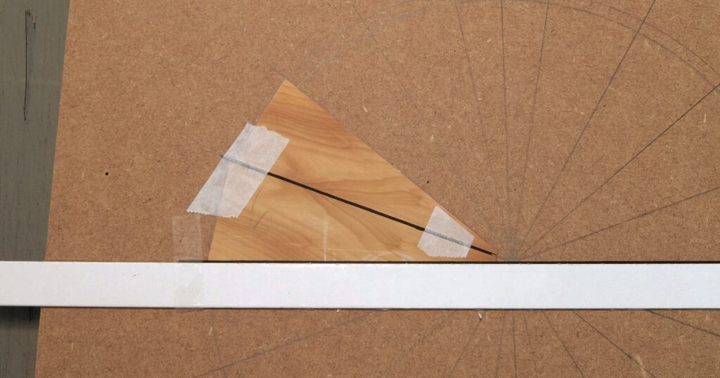 Wooden triangle with tape on drawing board.