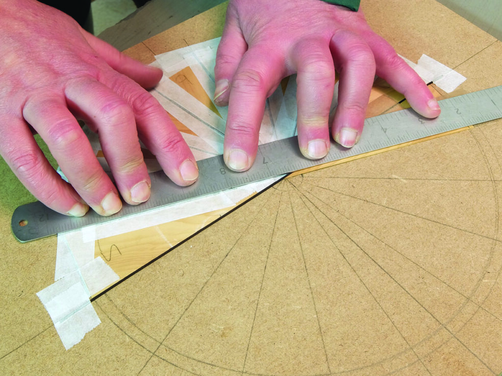 Hands measuring wood veneer with a metal ruler.