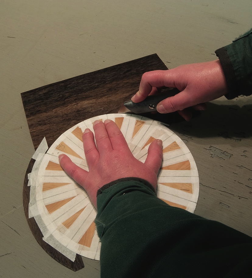 Craftsperson cutting wood veneer with knife