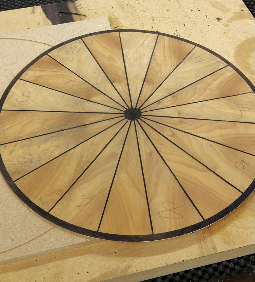 Wooden circular table top with radial patterns.