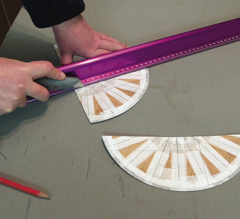 Person cutting shapes with knife and purple ruler.