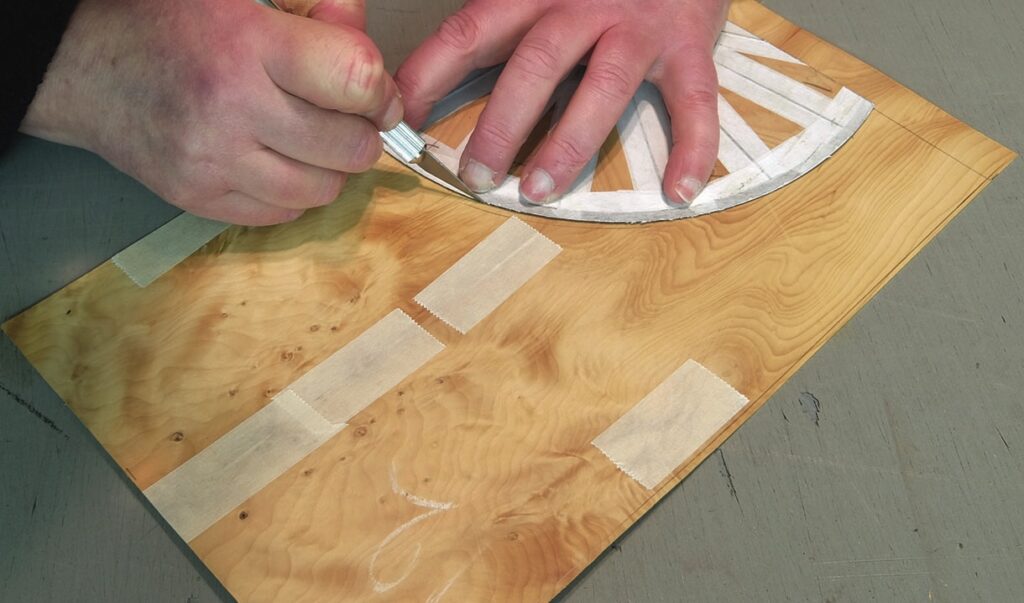 Person craftily cutting wood veneer design