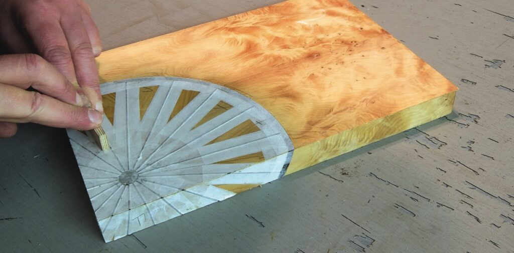 Craftsman measuring wood veneer marquetry design.