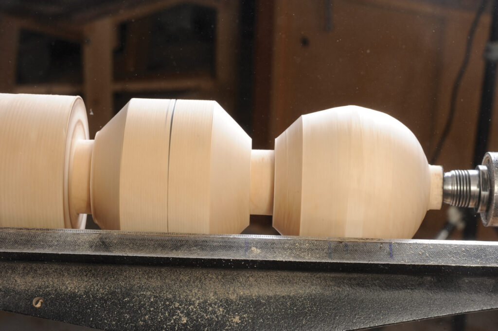 Wooden object being shaped on a lathe machine.