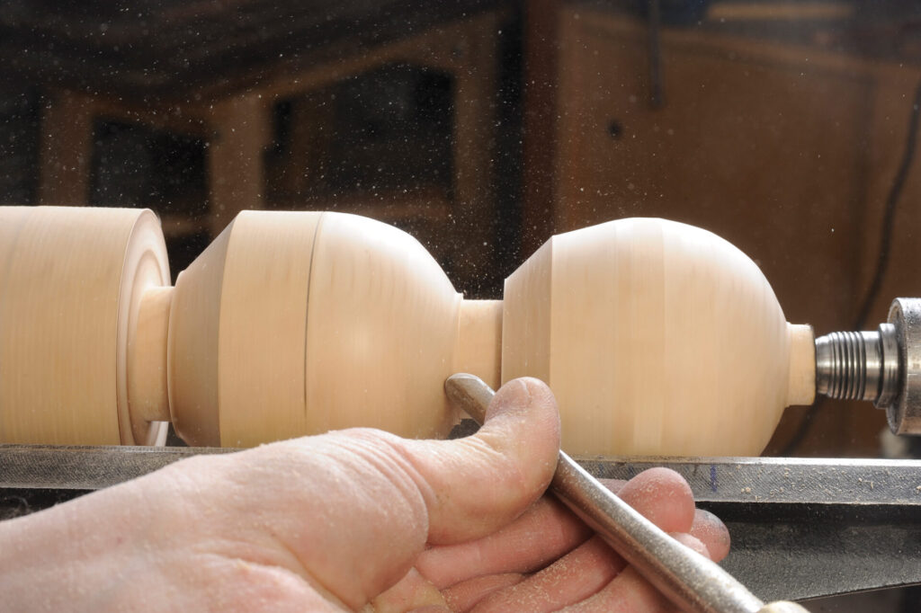 Craftsman using lathe to shape wood object.