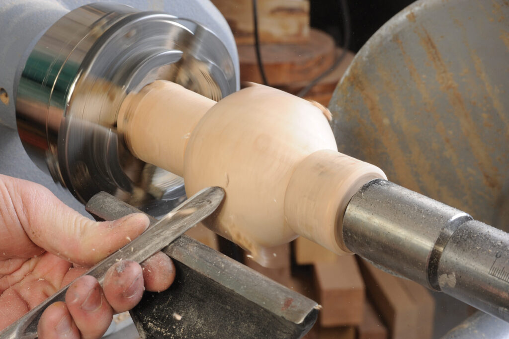 Woodturning on a lathe with a chisel.