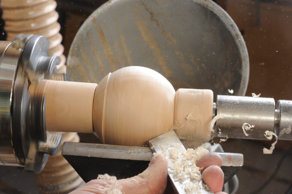 Woodturning a wooden spindle on a lathe machine.