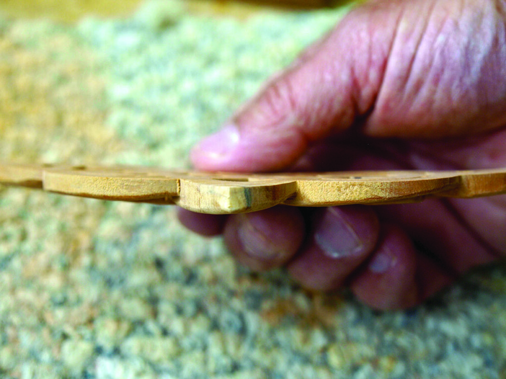 Hand holding a thin wooden object profile