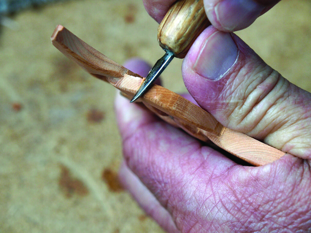 Person hand-carving wood with precision tool.