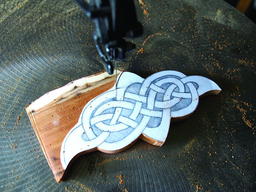 Celtic pattern being cut with fret saw on wood.