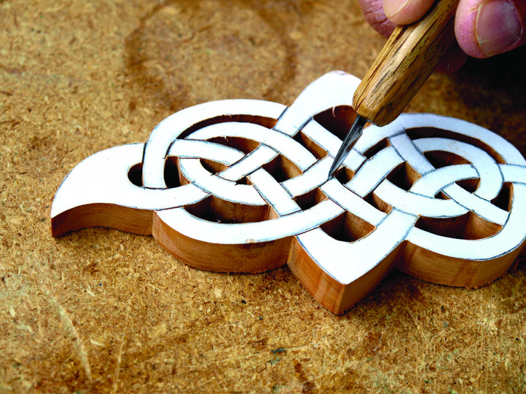 Wood carving with intricate Celtic knot design process.