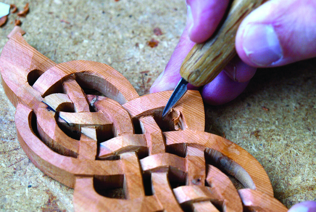 Intricate wood carving with a handheld chisel.