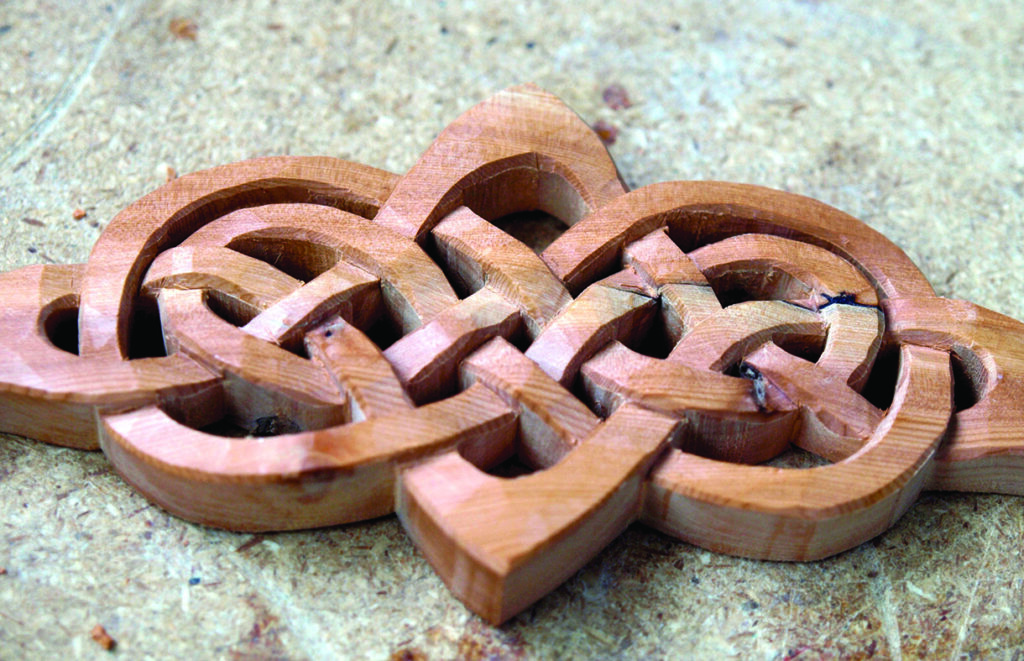 Intricate wooden Celtic knot carving on surface.