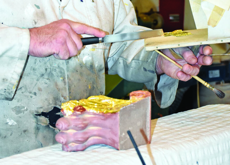 Chef using tools to apply edible gold leaf.