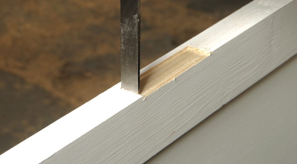 Chisel creating mortise in wooden surface