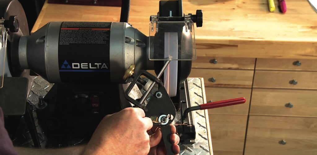 Person using sharpening tool on workbench.