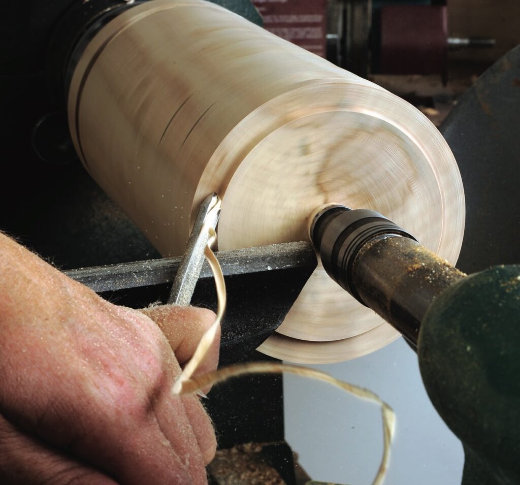 Woodturning with handheld chisel on a lathe.