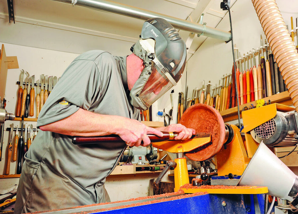 Woodworker using lathe machine in workshop