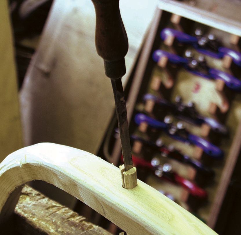 Chisel carving wood in workshop with tools nearby.