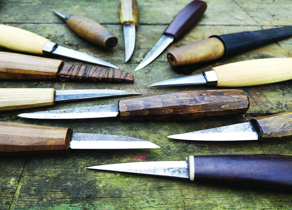 Various wood-handled carving knives on wooden surface