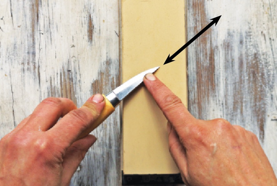Knife being sharpened on whetstone