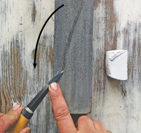 Sharpening knife with stone on wooden table.