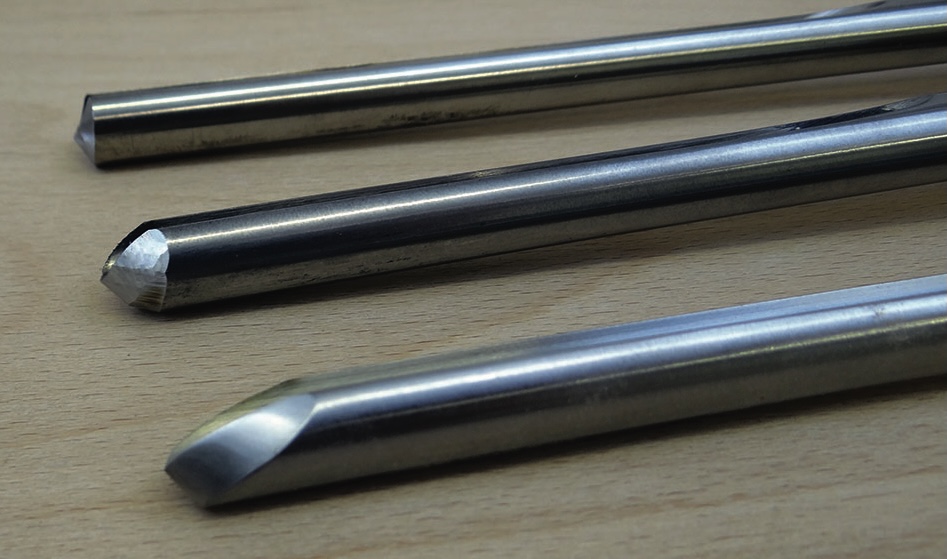 Three carbide-tipped engraving tools on wood surface.