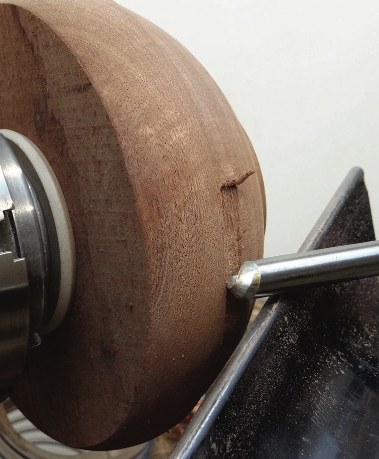 Wood on lathe being shaped by chisel.