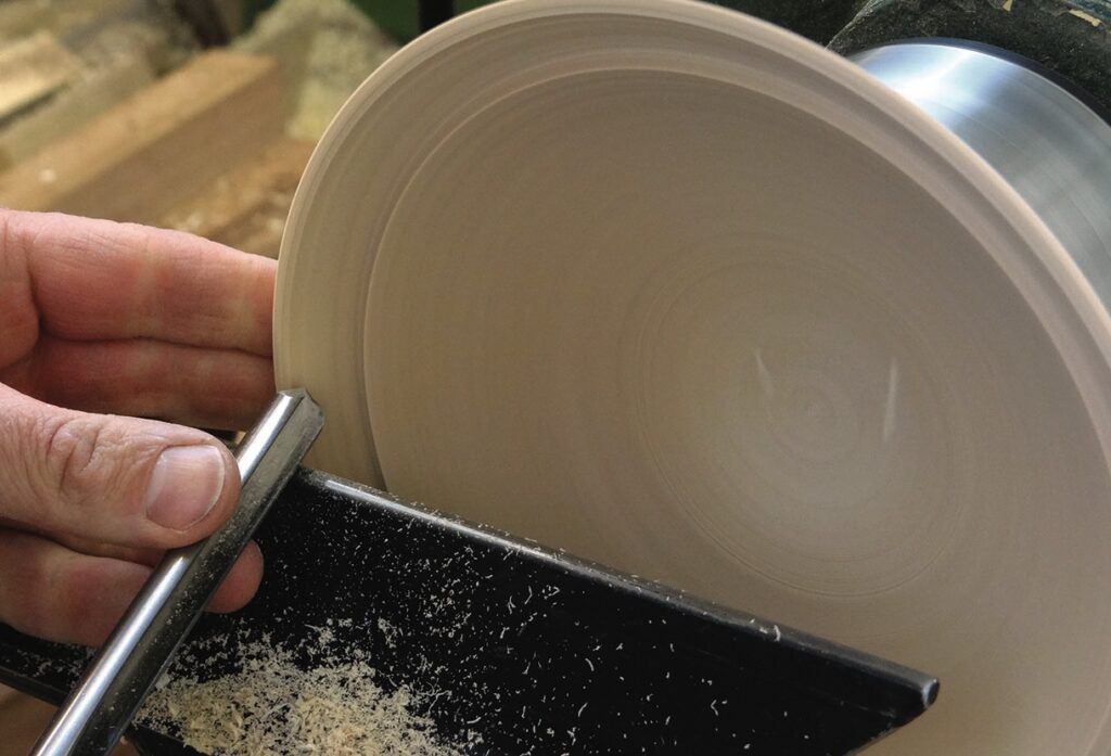 Hand using chisel on spinning wood lathe