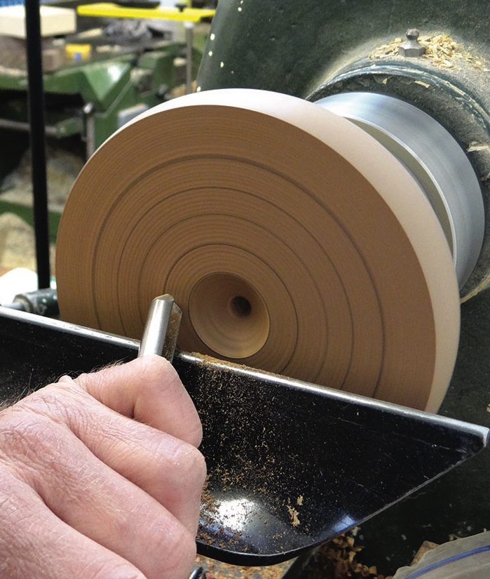 Person shaping wood on lathe tool