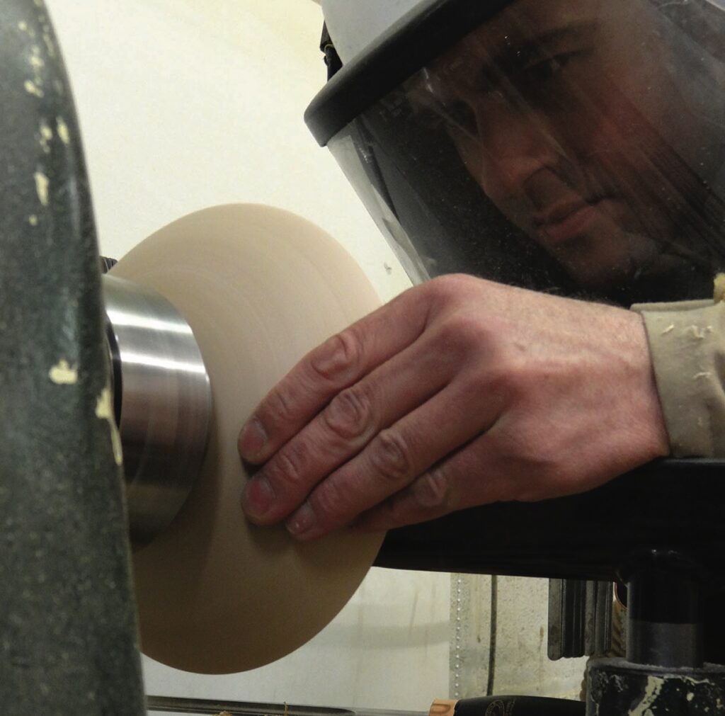 Woodturner crafting a bowl on a lathe machine.