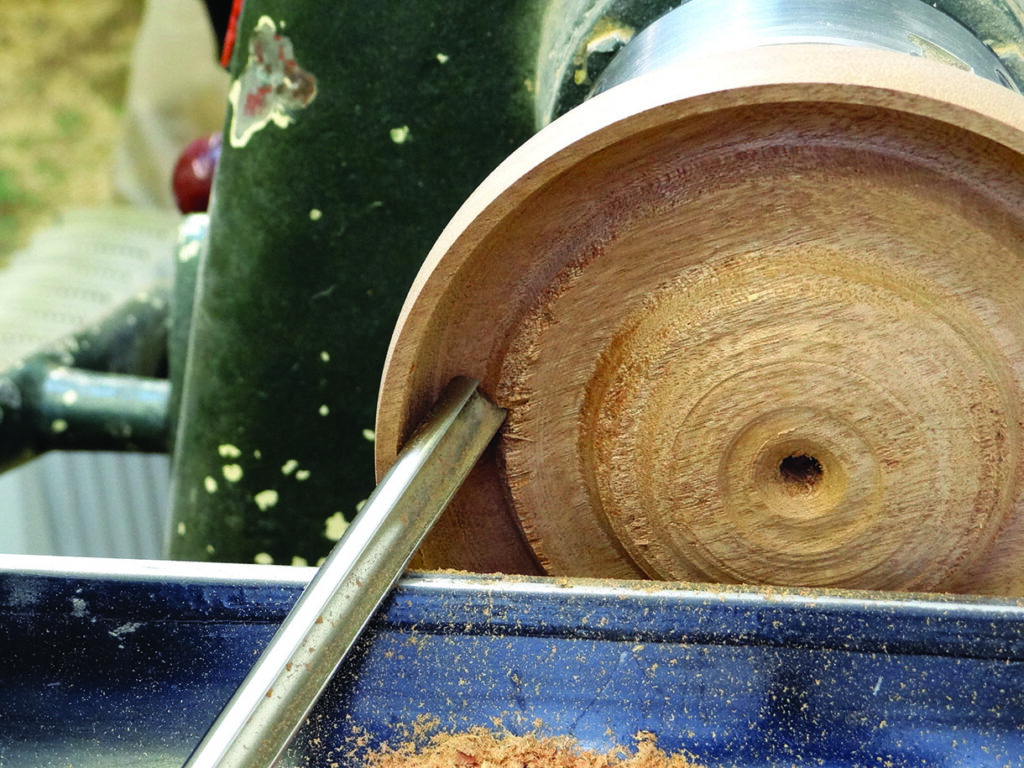 Woodturning with a chisel on a lathe.